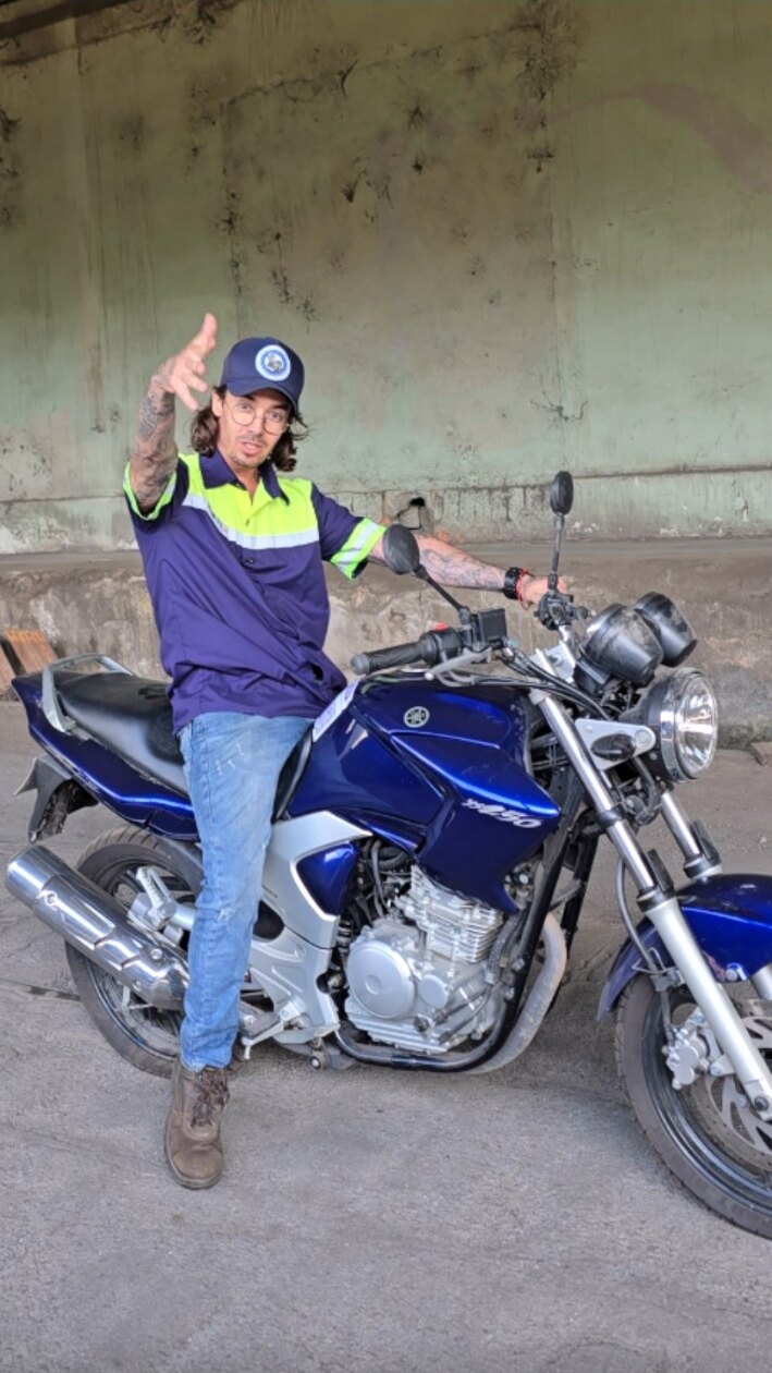 Leandro Harry Potter de uniforme ao lado de uma motocicleta